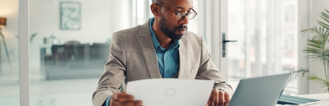 Business owner reviewing financial documents and working on a laptop, illustrating management of an owner-only 401(k) retirement plan for a self-employed professional.