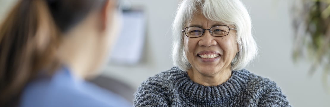 Mature woman smiling at medical professional.